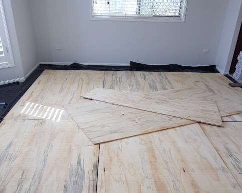 Plywood sheeting being laid over a moisture barrier